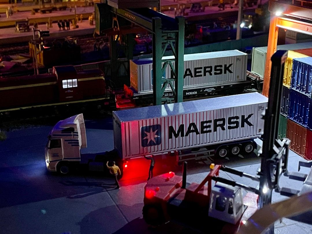 Miniatyrlandskap av logistikterminal med lastbilar och containrar.